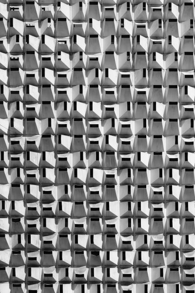 Black and white photograph of an architectural facade made entirely from cubes, repetitive pattern, monochromatic color scheme, symmetrical composition, geometric shapes, urban setting, modern design, symphony in detail, high resolution photography. The photograph depicts an architectural facade in the style of modern design with a repetitive pattern of cubes, a monochromatic color scheme, symmetrical composition using geometric shapes, and is set in an urban environment. The photograph captures these details with high resolution photography. --ar 85:128