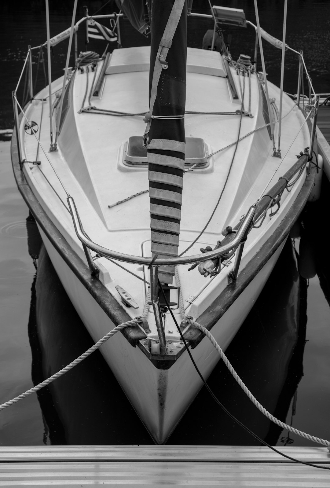 a close up of the front bow and deck, moored at dock with rope in monochrome style, a small sport yacht with white sails in an old port of A vareira, 2053 year, nikon d840, kodak film grain, photo realistic, hyper detailed, high resolution –ar 43:64