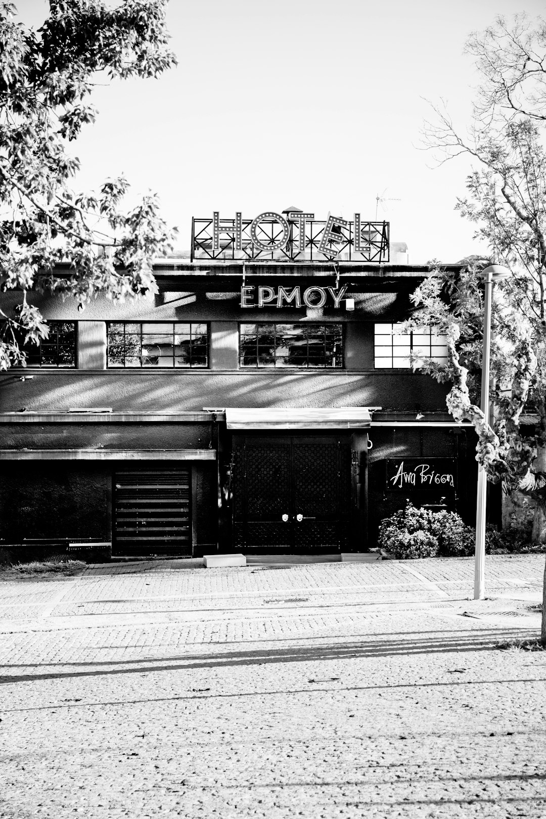 Black and white photography of an old club building with the sign “Emyo” written on it, in the Galita neighborhood. The photo has a minimalist, black and white style reminiscent of raw photography in the style of street photography. –ar 85:128