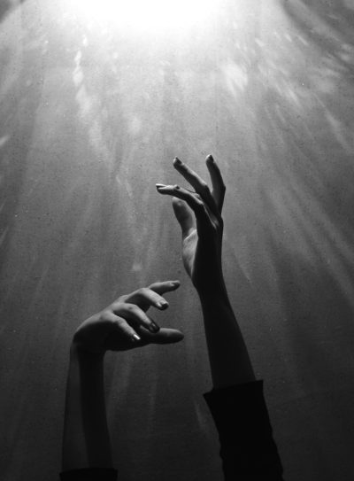 hands reaching out towards the light, underwater photography, grainy style in the style of film noir, dramatic lighting, atmospheric perspective, shot on hasselblad h6d400c medium format camera --ar 47:64