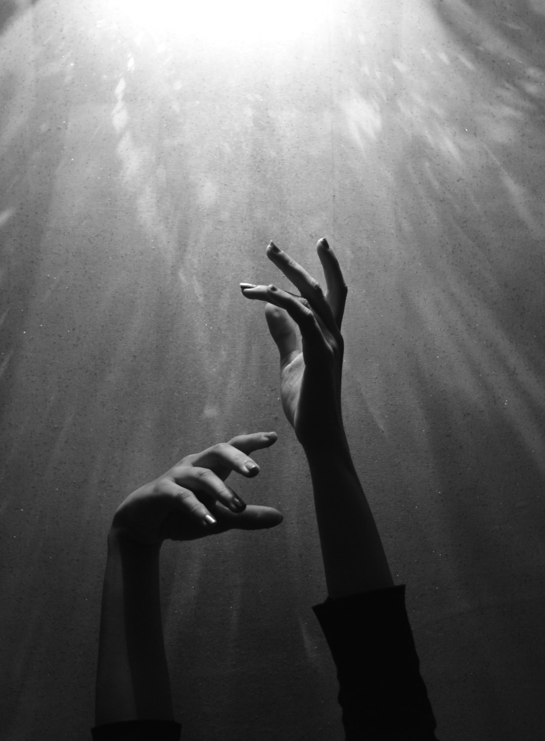 hands reaching out towards the light, underwater photography, grainy style in the style of film noir, dramatic lighting, atmospheric perspective, shot on hasselblad h6d400c medium format camera –ar 47:64