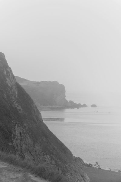 black and white film photograph of the coastline in Big Sur, with cliffs and foggy weather, shot in the style of Leica M6 --ar 85:128
