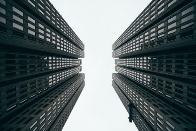 A photo of two tall buildings from below, symmetrical, minimalist, architectural photography, white background, cinematic, dark tones, sharp focus, high resolution --ar 128:85