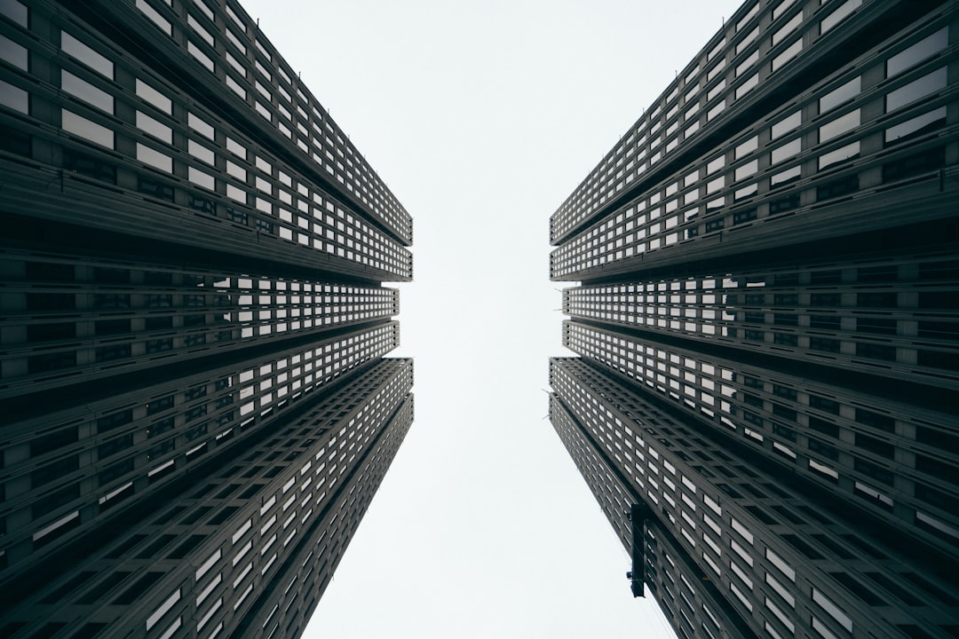 A photo of two tall buildings from below, symmetrical, minimalist, architectural photography, white background, cinematic, dark tones, sharp focus, high resolution –ar 128:85