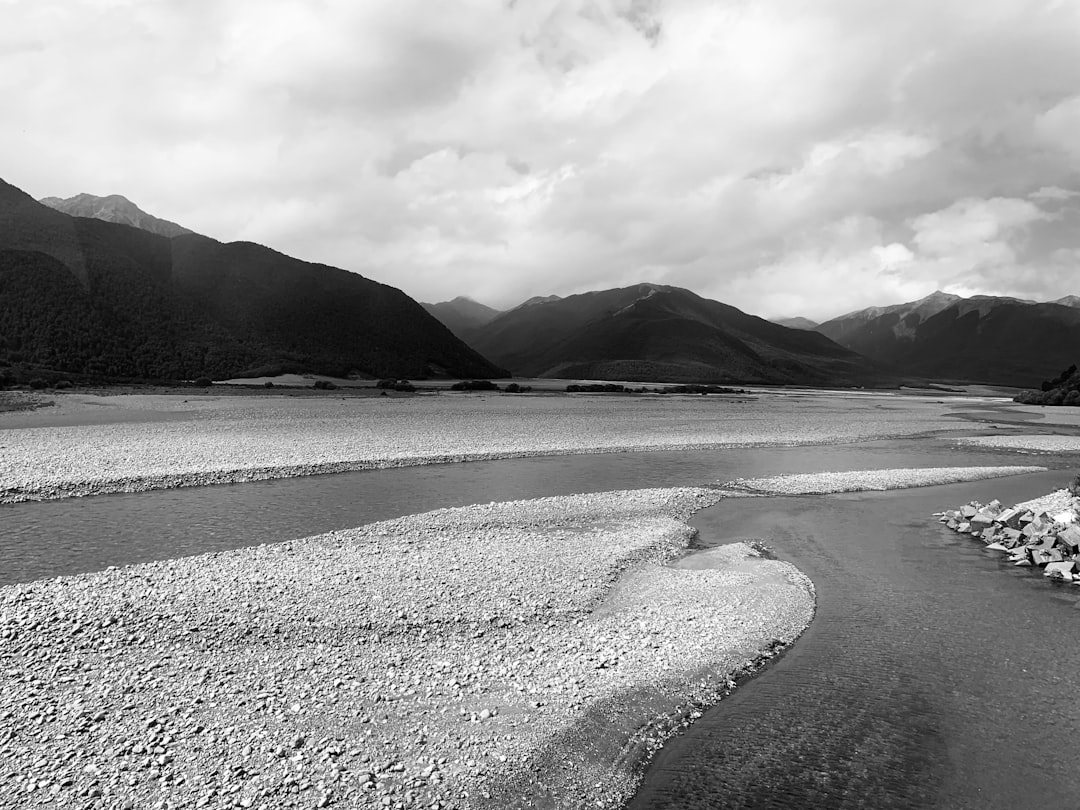 Black and white photography of the Hanbo River in New Zealand, surrounded mountains. The river is dry with rocks on its surface in the style of [Ansel Adams](https://goo.gl/search?artist%20Ansel%20Adams). –ar 4:3