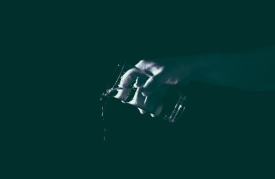 dark background, close up of a hand holding a camera in low light, white and dark green colors, minimalism, cinematic style --ar 128:83