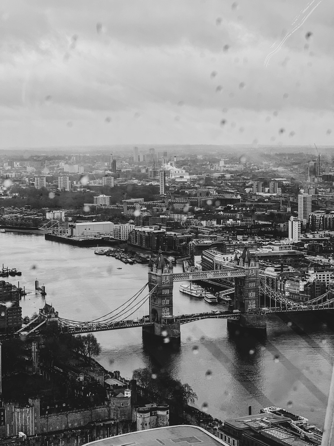 Black and white photo of London, Tower Bridge, skyline, rain drops on the glass, cityscape, high angle shot, wide view, in the style of Canon EOS R5. –ar 3:4