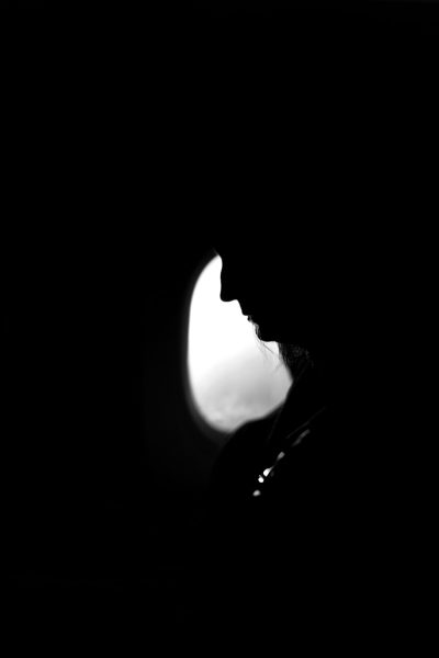 A black and white photograph of the moon, with only its silhouette visible against an allblack background. A woman's head is seen in profile from below, silhouetted by her shadowed figure on top of it. The contrast between light and dark creates depth to both elements within the frame. This minimalistic composition evokes tranquility and mystery. Shot with a Leica M6 film camera using Ilford HP5 Plus 400 Film --ar 85:128