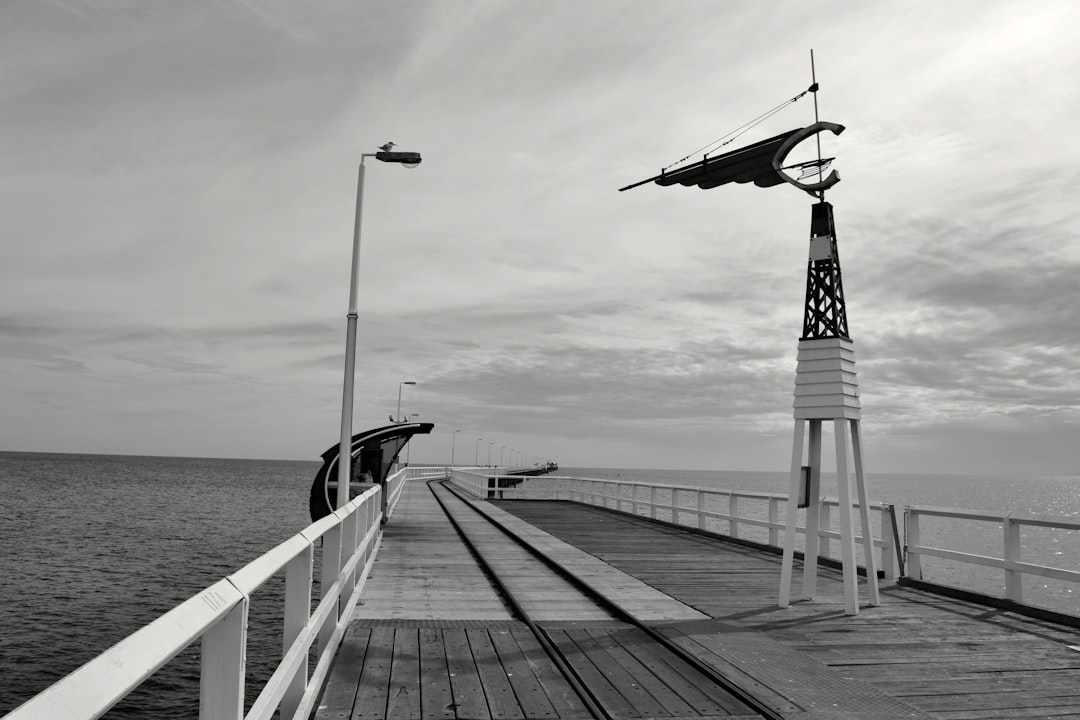 Black and white photograph of the old pier in Road to Py Moskvy, a wind vane on one side of the pier, in the style of by unknown artist. –ar 128:85