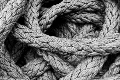 A detailed black and white photograph of an old, frayed rope with complex knotwork, symbolizing strength in graphics design. The texture is richly textured, capturing the intricate details that highlight its historic nature as part of nautical culture. This visual metaphor for resilience could be used to represent various aspects such as a fire safety plan or technical drawing in the style of nautical culture. --ar 128:85