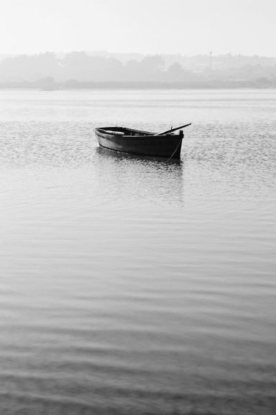 Black and white photography of a small boat floating on a calm lake in the style of minimalism. --ar 85:128