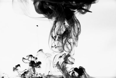 Black ink in water, smoke, white background, photography style, simple and clean composition, high definition, high resolution, high detail, black smoke, smoke swirling around the middle of an abstract shape, with a few small flowers scattered on it. The ink is flowing from top to bottom, creating a dynamic feeling. High contrast between light and dark tones creates visual impact. A wideangle lens captures entire picture. Black ink floats at different heights, forming an interesting pattern. It's like liquid art. --ar 128:85