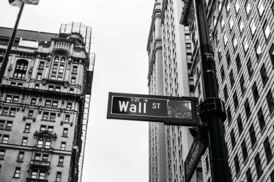 Wall Street sign, black and white photography, high resolution, Canon R5 camera, wide angle lens, iconic financial district buildings in the background, stock market trading graphic on street pole, focus on cityscape and clear sky. Black & White Photography in the style of Canon R5. --ar 128:85