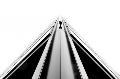 Minimalist black and white photography of a tall building with a triangular shape and high contrast against a white background with high resolution in the style of HDR architectural photography with a straight view looking up at the top of a skyscraper with geometric architecture and a symmetrical composition of a modern design with sleek lines and a monochromatic color scheme from a high angle perspective showing sleek metal details in a minimalist style. --ar 32:21