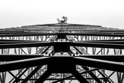 Black and white photo of the top view of an iron construction, the bottom is a large structure with many steel beams. The main focus should be on one central beam in front that leads to another smaller peak at its center where there's some equipment working or building something, black & White photography, high contrast, high resolution, high definition, HDR, soft light, 35mm lens, shot by canon eos r6 mark II --ar 128:85