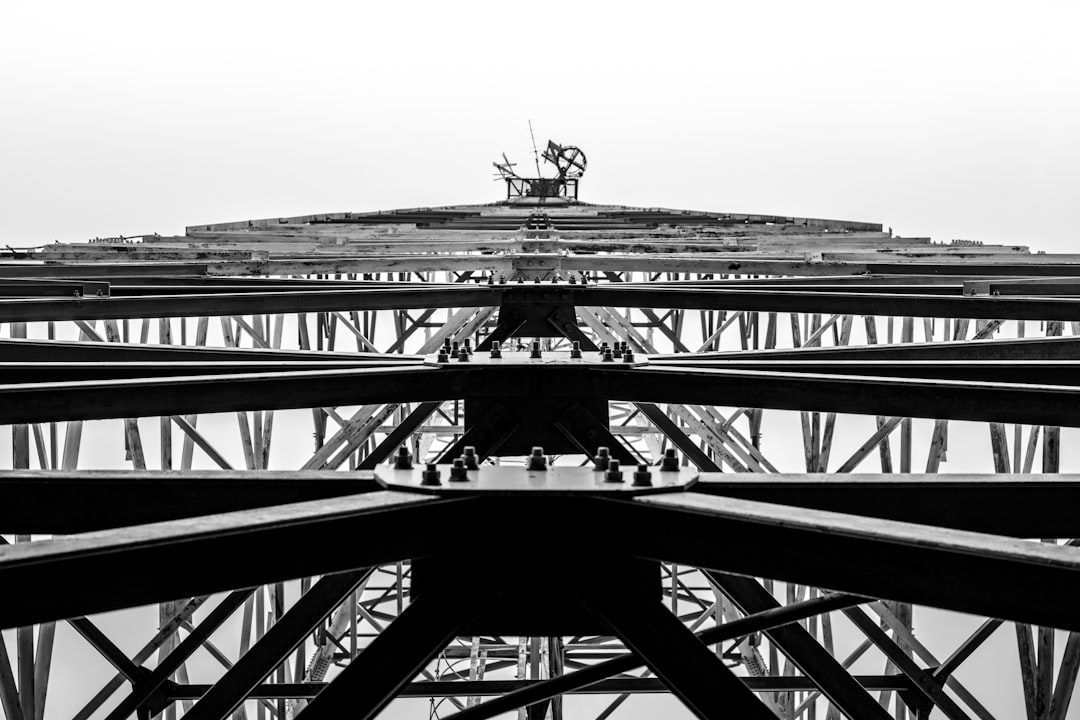 Black and white photo of the top view of an iron construction, the bottom is a large structure with many steel beams. The main focus should be on one central beam in front that leads to another smaller peak at its center where there’s some equipment working or building something, black & White photography, high contrast, high resolution, high definition, HDR, soft light, 35mm lens, shot by canon eos r6 mark II –ar 128:85