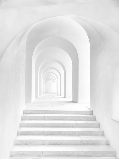 A white arch with stairs leading upwards to the right, in a symmetrical composition against a white background. The simple style uses soft light and low saturation for a monochrome tone. The overall effect is clean and calm, feeling like an open space that opens up to another world. --ar 3:4