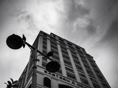 A black and white photo of the top floor corner exterior wall of a hotel with "EASTʻ.Sâtler & Driv" written on it, a large street light in front of the building, a cloudy sky, taken from a low angle, captured with a canon eos r5 camera. --ar 4:3