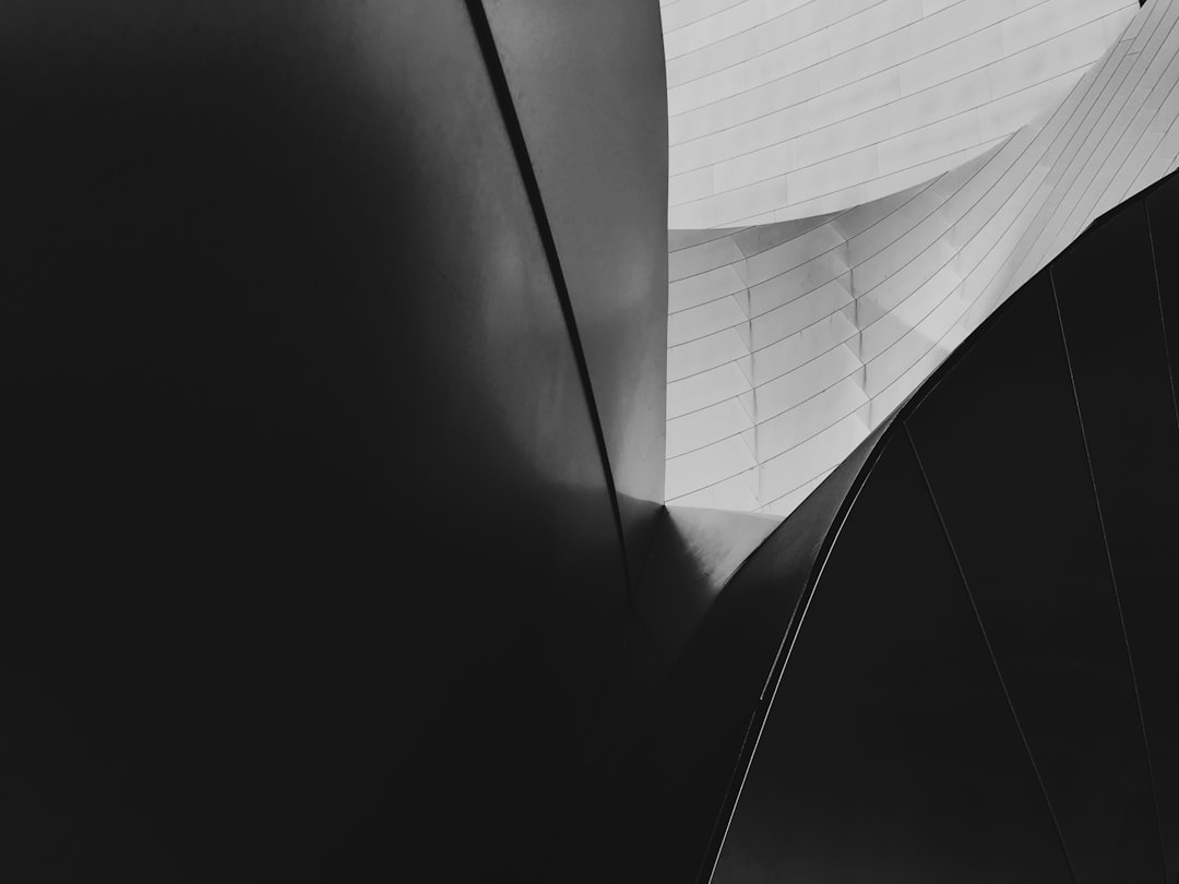 Black and white photograph of the iconic Disney Microsoft Center in Los Angeles, focusing on its unique architecture with sharp lines and geometric patterns. The building’s exterior is highlighted against a dark background, emphasizing architectural details. High contrast lighting creates depth to highlight textures and shapes. Minimalist composition, closeup shot capturing elements like angular structures and curved edges in the style of architectural photography. –ar 4:3