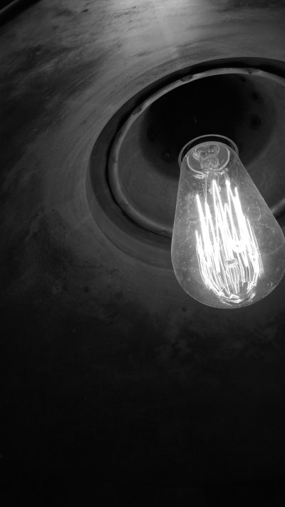 Close up of a light bulb hanging from a ceiling, in the style of [Dave McKean](https://goo.gl/search?artist%20Dave%20McKean), black and white, low angle shot, concrete floor, a circular hole in the center of the frame, simple. --ar 9:16