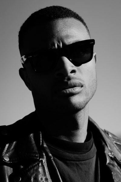 a black and white portrait of young Michael B Jordan wearing aviator sunglasses, a leather jacket and tshirt, 35mm lens, f/2.8 --ar 85:128