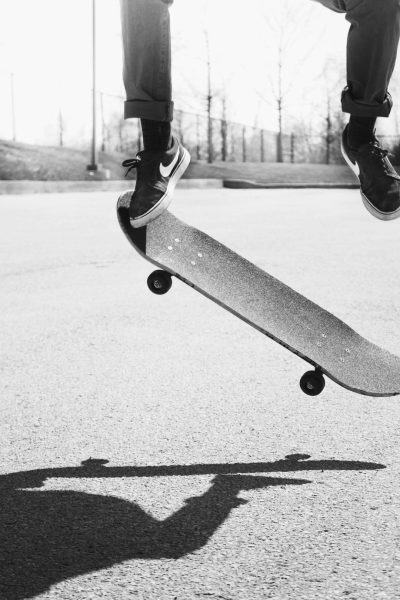 A black and white photo of someone doing an ollie on their skateboard, low angle shot, shot from below, extreme close up shot, skate park background, in the style of unsplash photography, minimalistic aesthetic --ar 85:128