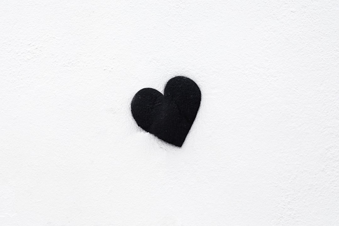 Minimalist black heart on a white background, symbolizing love and romance for Valentine’s Day or wedding designs. White background in a flat lay style. Black Heart On A Snowy Wall, closeup shooting in 4k ultra realism with high detail in the style of Kodak vision3 50 film look using an f2 lens. –ar 128:85