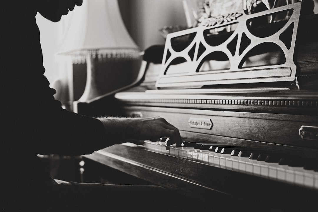 A black and white photograph of an antique upright piano, with the focus on one hand playing it. The scene is set in an old house living room, with soft lighting highlighting intricate details like wood grain or metal elements. A man’s arm extends from off screen as he plays the keys. The composition captures both closeup shots of his hands and more distant views showing the overall structure of the instrument. Shot in the style of [Ansel Adams](https://goo.gl/search?artist%20Ansel%20Adams). Nikon D850, f/2 lens, 35mm focal length, shallow depth of field. –ar 128:85