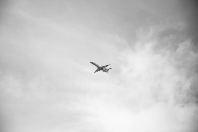 Black and white photo of an airplane flying in the sky, minimalist style, taken with a Fujifilm XT4 camera in the style of minimalism. --ar 128:85