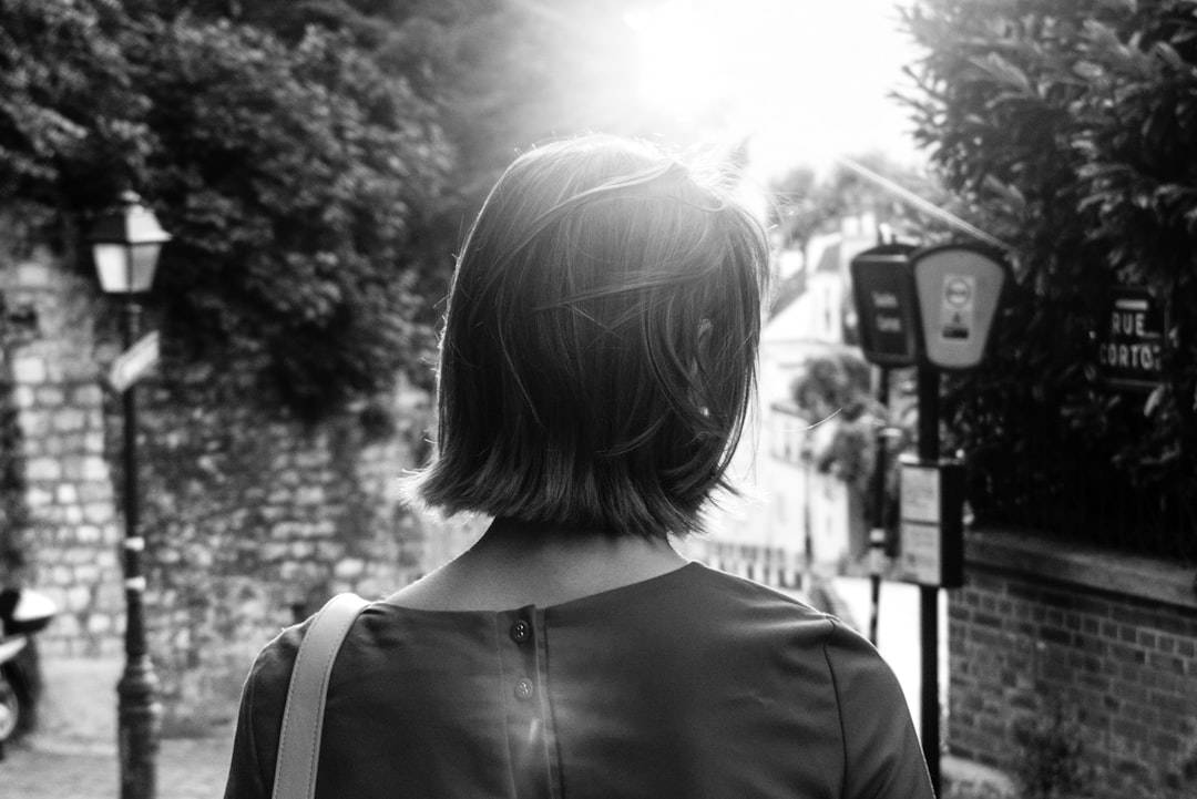 A woman with short hair is seen from behind walking in the streets of old London. The sun is shining and there is an atmosphere of mystery around her. Black and white photography, using a Fujifilm XT4 camera, with an aperture of f/8 and a grain film texture effect. The image is in the style of black and white photography. –ar 128:85