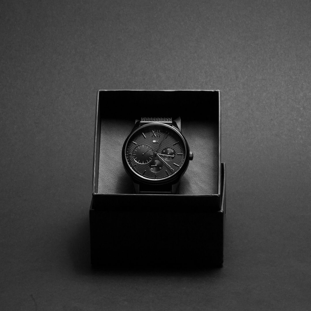 Black watch in a black box on a grey background, minimalistic product photography in the style of no artist.