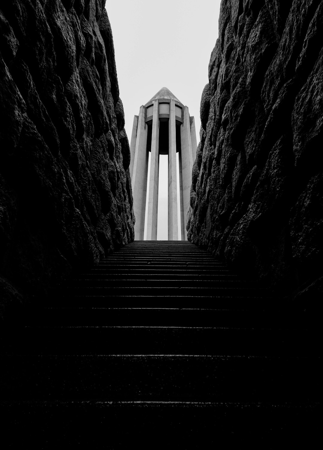 monument to the fallen soldiers, stairs leading up to it, tall monolithic tower in center of frame, surrounded by black rocks, symmetrical composition, black and white photography, high contrast, sharp details, shot on Hasselblad medium format film camera, sharp focus, depth of field –ar 23:32