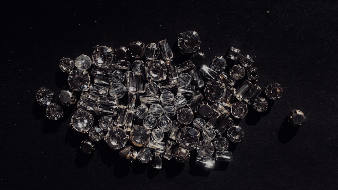 Top view of a pile of clear glass beads on a black background, in the style of product photography. –ar 16:9