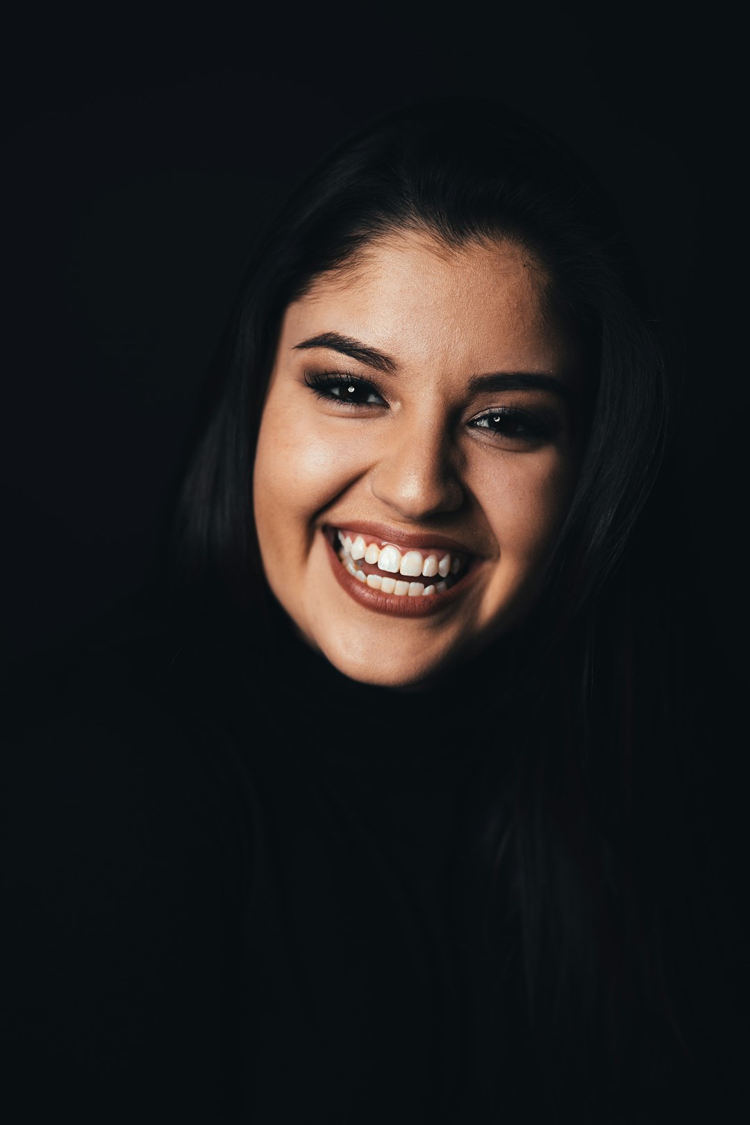 portrait of happy Latin woman, black background, soft light, in the style of fujifilm xh2s photo camera –ar 85:128