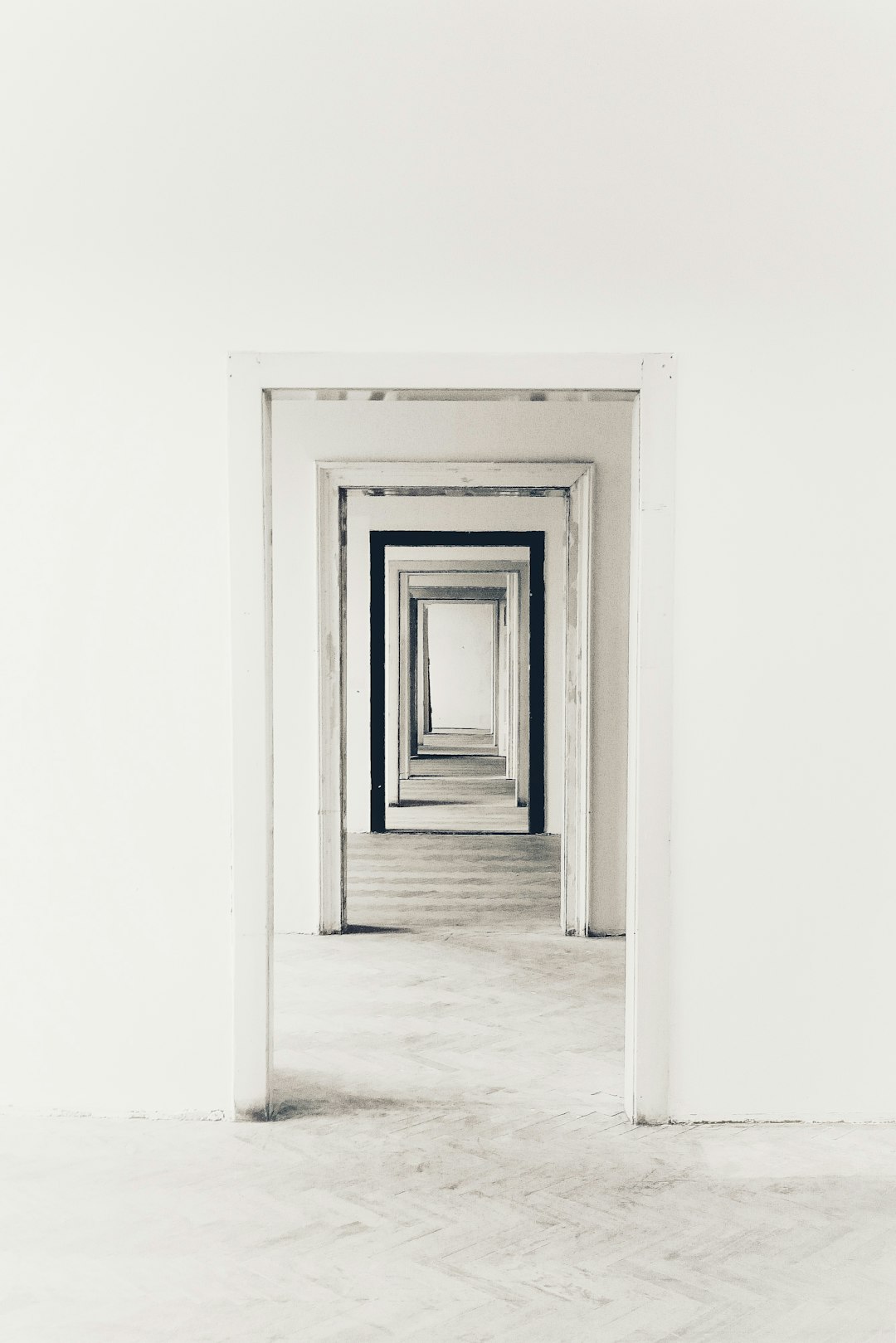 A minimalist composition of an empty room with white walls and floors, featuring multiple doorways leading to different rooms, creating the illusion that one is walking through endless doors. The overall effect should be a sense of disoriented time travel or infinite mirrors, evoking feelings of curiosity and surrealism in the style of surrealist artists. –ar 85:128