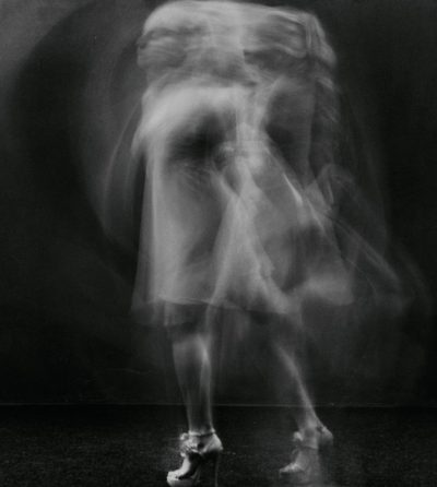 The blur of motion, the dance of body and spirit, captured in an ethereal photograph. Focus on the face of a female dancer in a short dress and high heels in the style of [Richard Avedon](https://goo.gl/search?artist%20Richard%20Avedon) against a dark background. --ar 57:64