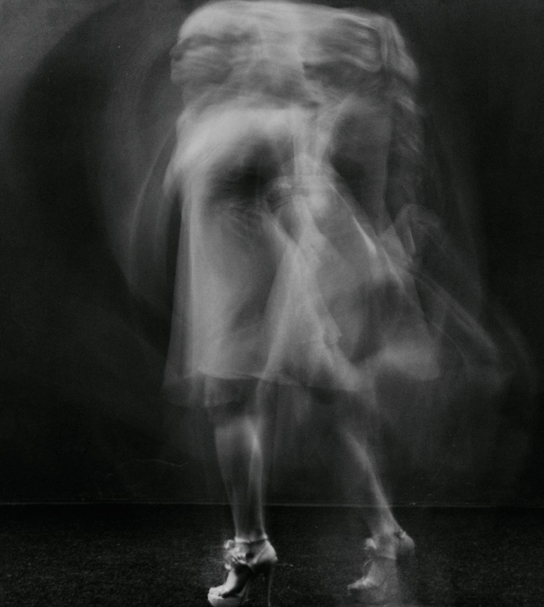 The blur of motion, the dance of body and spirit, captured in an ethereal photograph. Focus on the face of a female dancer in a short dress and high heels in the style of [Richard Avedon](https://goo.gl/search?artist%20Richard%20Avedon) against a dark background. –ar 57:64