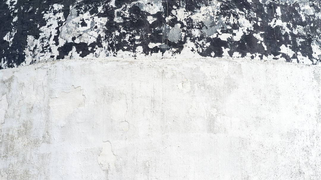 A white concrete wall with black grunge texture paint on the top and bottom of it, photographed flat, in high resolution of approximately 2K, in the style of flat lay photography. –ar 16:9