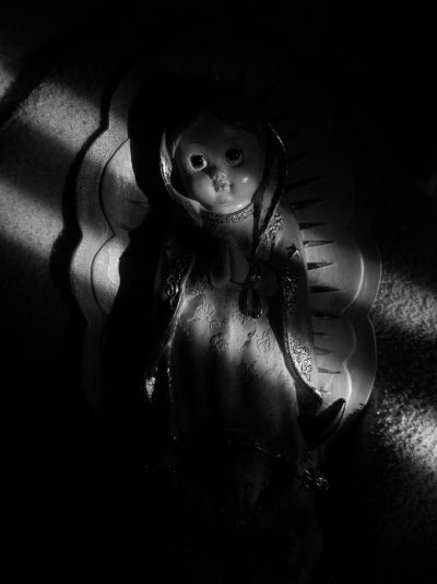 A black and white photo of an angel doll in the dark, with light shining on it from above in the style of no artist. --ar 95:128