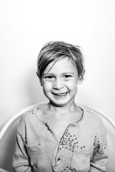black and white portrait of smiling boy, short hair in the style of [Rineke Dijkstra](https://goo.gl/search?artist%20Rineke%20Dijkstra) photo, studio background, simple with dirty stains --ar 85:128