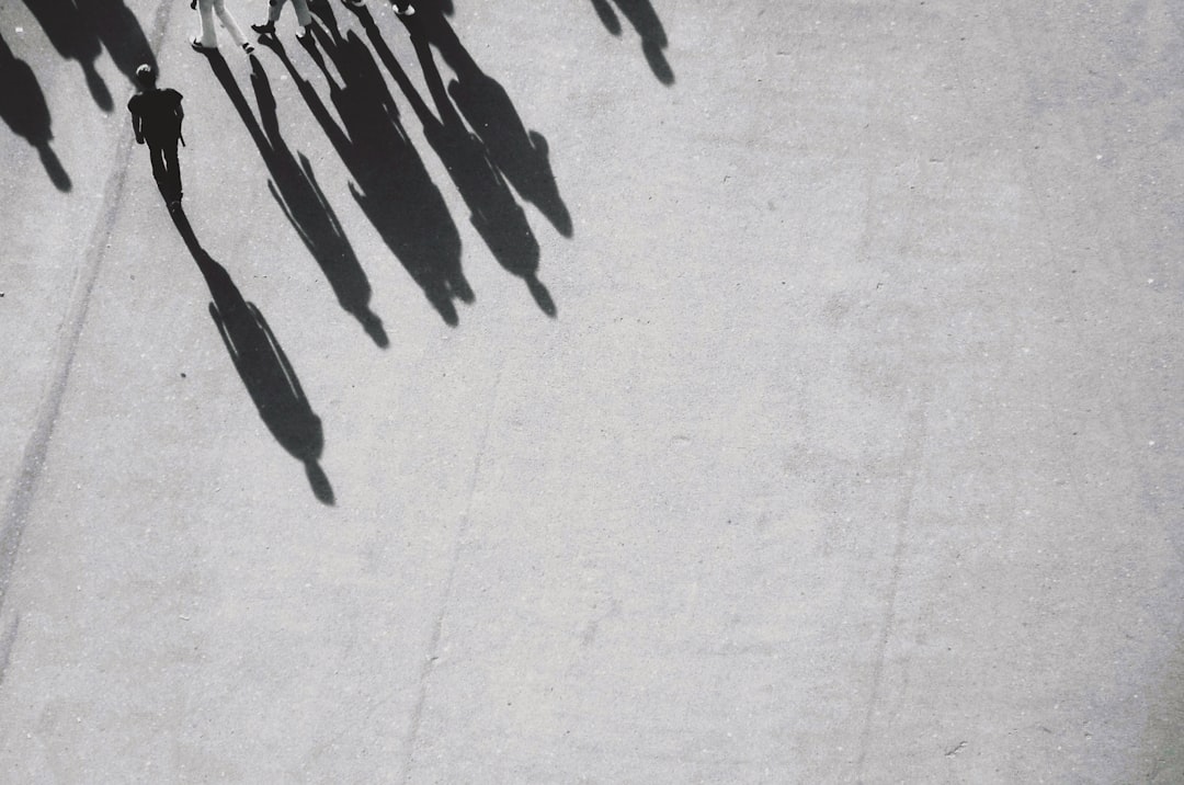 Close up overhead shot of shadows cast in the style of people walking on concrete, muted grey tones, minimalism, high contrast. –ar 32:21