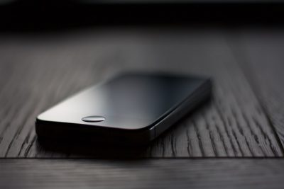 A close-up shot of an iPhone on a table, with a dark grey background and soft lighting, taken with high resolution photography, with insanely detailed and fine details, isolated on a black background, in the style of stock photography. --ar 128:85