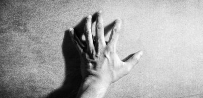 A hand with five fingers is reaching out from the left side of an empty canvas, creating shadows on its surface. The background features soft light and gentle tones that highlight details in monochrome black and white. The style is reminiscent of an artist working in the style of [Caravaggio](https://goo.gl/search?artist%20Caravaggio). --ar 64:31