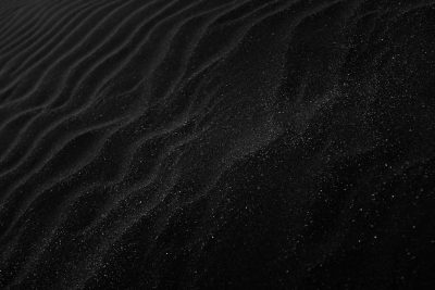 Black sand texture background. Sand ripples in the wind. Dark desert dunes with a starry night sky. A dark sand pattern. A minimalist black and white design. A dark abstract texture. A shiny grainy sand surface in the style of starry night. --ar 128:85