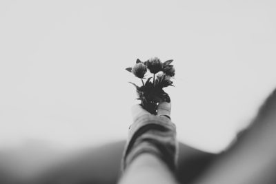 black and white photo of a hand holding flowers, minimalistic with a blurry background, in the style of unsplash photography. --ar 128:85