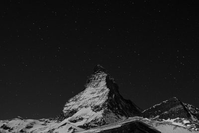 Black and white photo of the peak of Matterhorn mountain at night, starry sky, snow on top of the mountains, simple, minimalistic, high contrast, black background, photography, in the style of canon eos r5. --ar 128:85