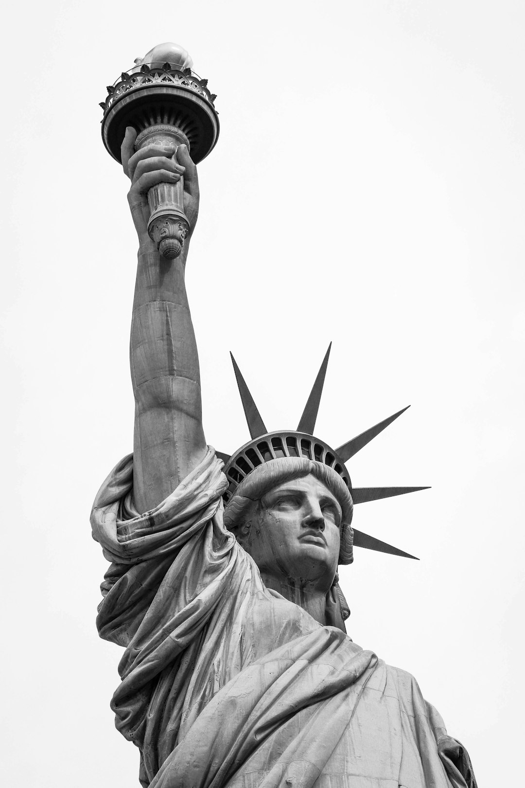 Black and white photo of the Statue of Liberty, holding up her torch in one hand, white background, high resolution, high quality, high detail, photography, in the style of Canon R5 digital camera, macro lens, 20mm f/8.0 aperture. –ar 85:128