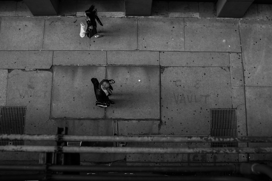 A top-down view of an urban street, two people in the distance having fun doing acrobatic poses. Concrete floor and walls. Architectural photography in the style of black and white photography, low angle shot, Leica M6 with Summilux at f/8 aperture. –ar 128:85