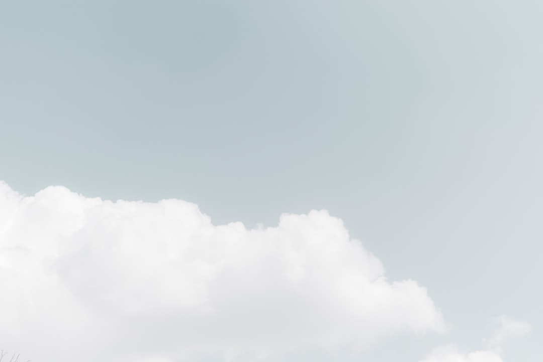 Photo of a white cloud in the sky, against a pastel background, in a high quality style, in the style of unsplash photography, with a minimalist style, using pastel colors of light blue and gray. –ar 128:85