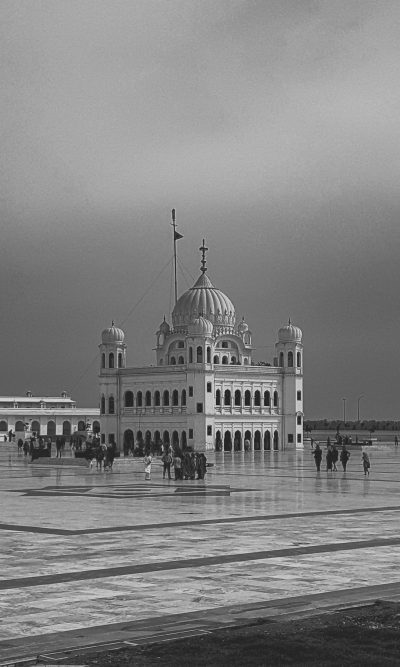 Gurudwara in the middle of sea, people walking around groram style building, black and white, old photo, wide shot, cinematic --ar 19:32